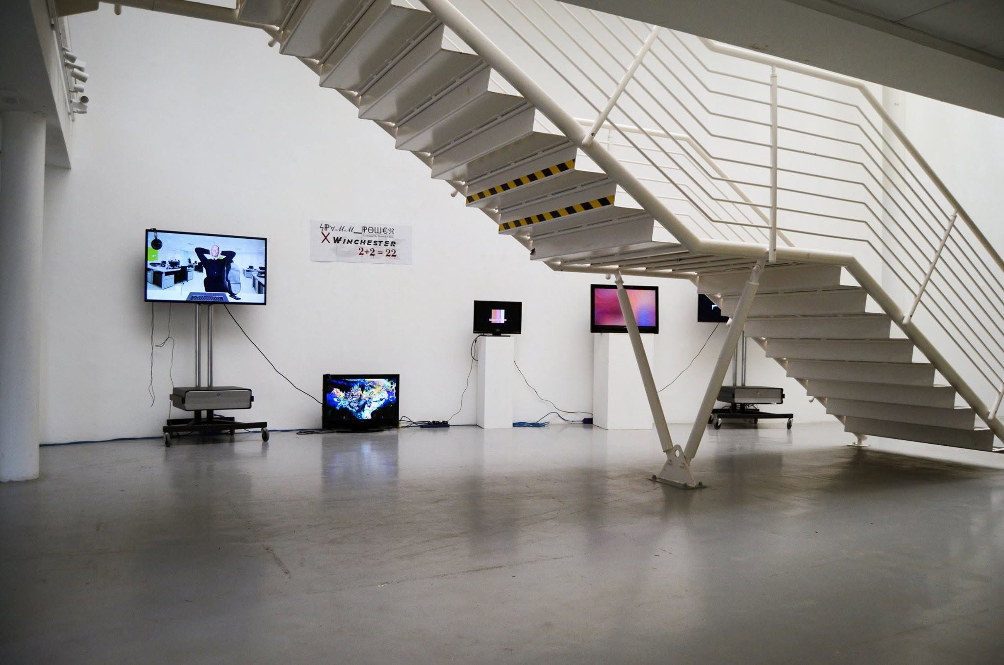 SPAMM Power exhibition screens beneath a white staircase